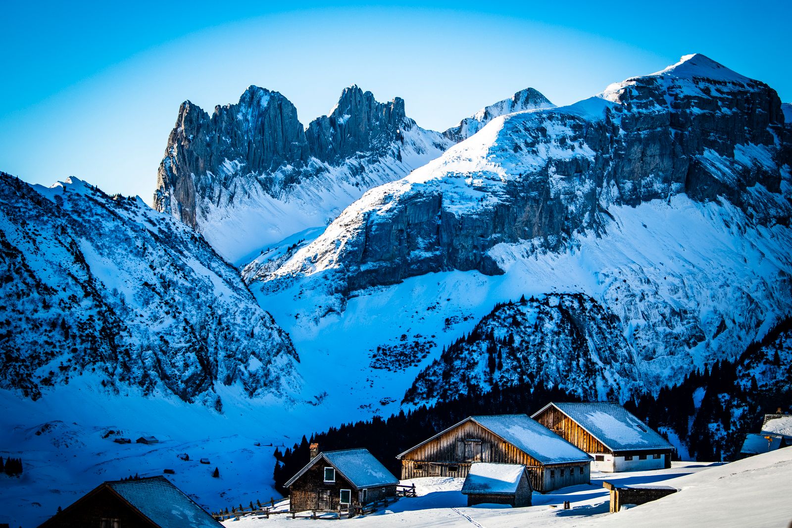 Snow on the hills and wooden farmhouses below the Alpstein, in Appenzell