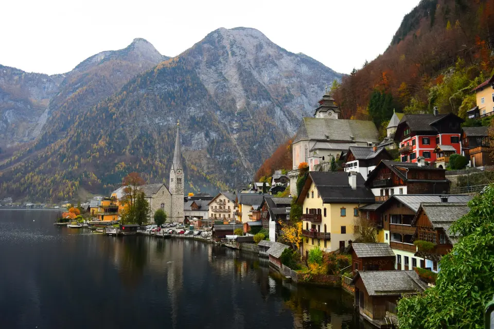 photo of an austrian city on the border of a lake with moutains in the background, in fall