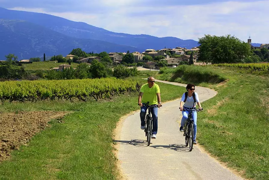 A couple cycling a Provence village lane