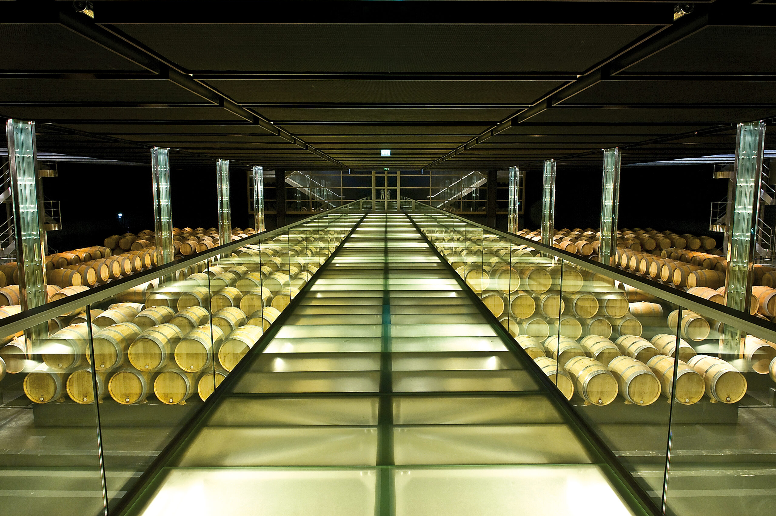 A vaulted Bordeaux cellar tunnel receding into warm light