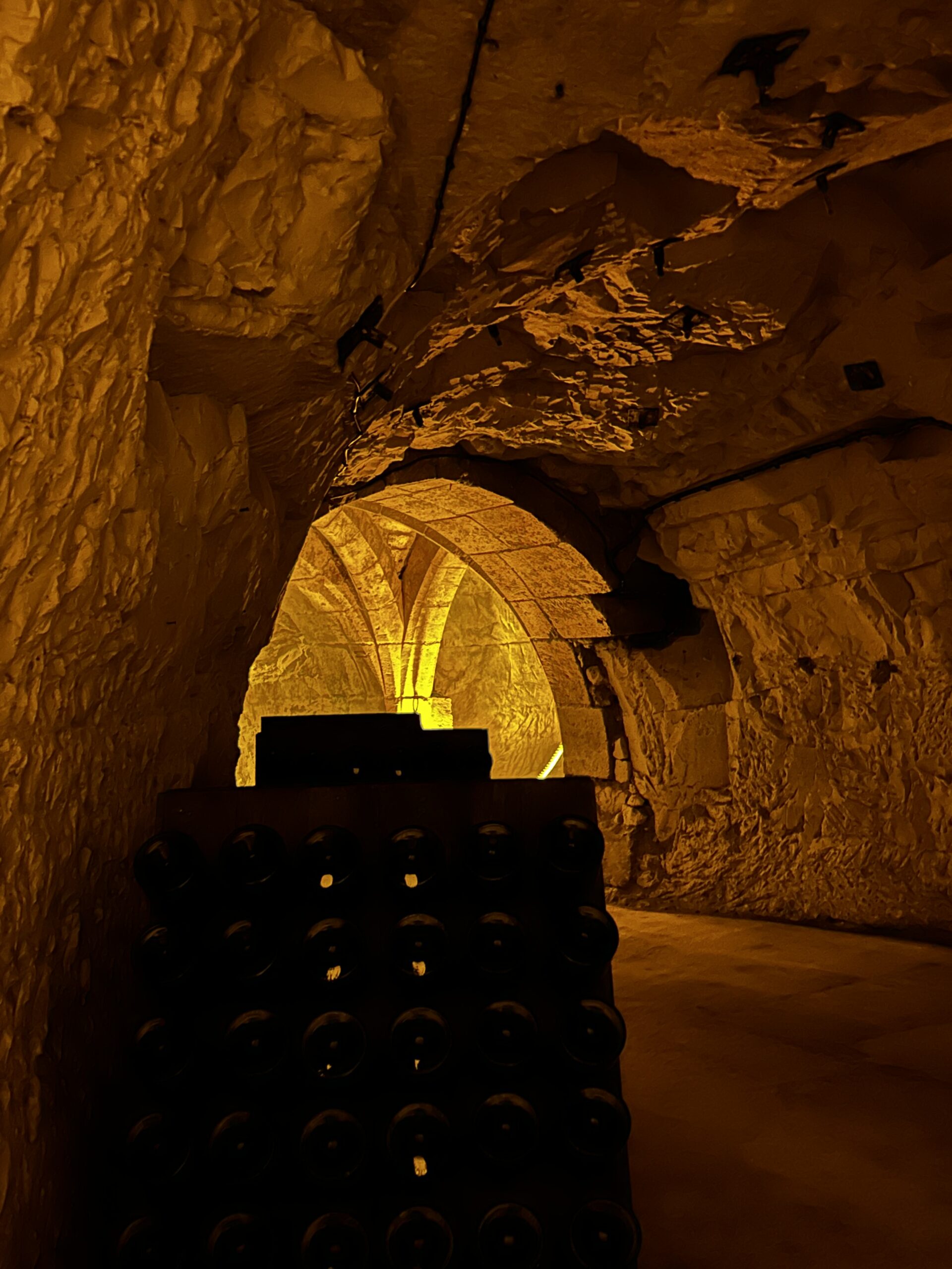 Beneath Europe: Roman Cellars, Cave Cities and a Lake in the Dark 3 Champagne bottles stacked before a lit chalk vault in a crayère